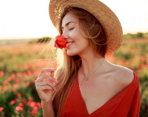 mulher-loira-romantica-com-flor-na-mao-caminhando-no-campo-de-papoulas-incrivel-cores-quentes-do-sol-chapeu-de-palha-vestido-vermelho-cores-suaves_273443-2841